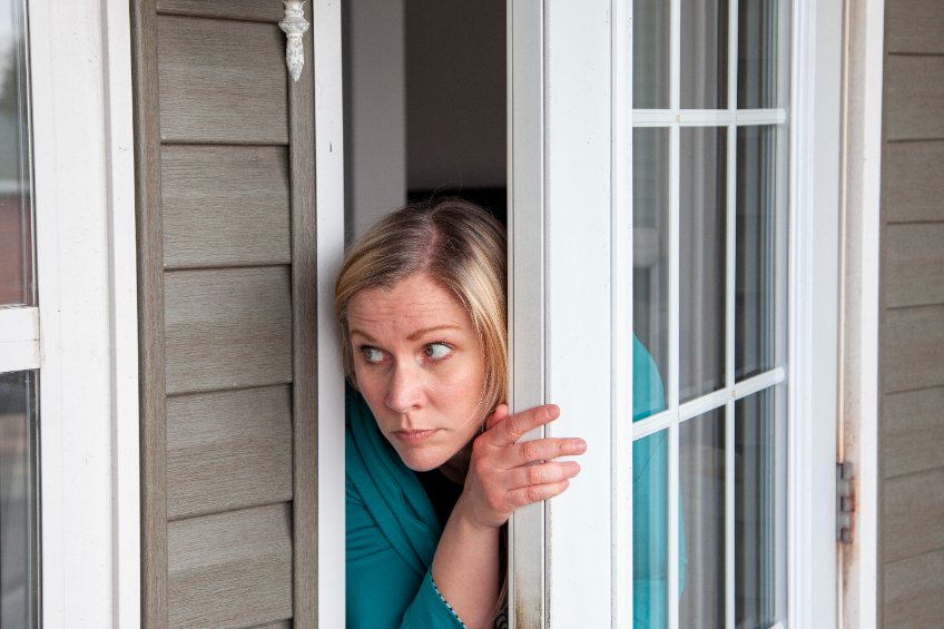 Fearful woman looking out the door